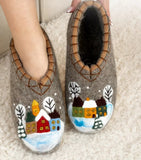 Pair of gray woolen slippers house boots with winter houses scene design on a light background