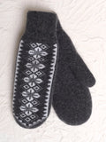 A pair of dark gray knit woolen mittens with a white geometric pattern on one mitten, displayed on a textured white background.