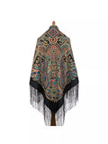 Colorful patterned oversized wrapping  shawl with black fringe on a white background