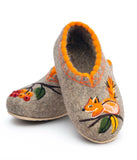 A pair of modern, fashionable gray felt slippers made from 100 percent natural organic wool. The slippers highlight premium craftsmanship with contrasting orange blanket stitching around the top opening. The front sections are uniquely decorated, one with a stylized orange squirrel clutching a green and yellow acorn, and the companion slipper with a delicate red berry branch design.