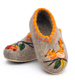 A fashionable winter outfit focusing on artisanal footwear Slavic valenki made from premium 100 percent natural sheep wool with a squirrel and rowanberry. The slippers are upgraded with a durable, non-slip rubber bottom sole designed for slippery urban conditions.