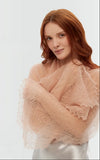 A woman wearing a wrapping pashmina shawl made of organic goat wool with lace gossamer ornaments in vintage beige.