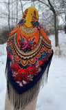 Colorful cashmere yellow shawl with floral patterns and fringes in a snowy landscape. A warm and cozy winter wool scarf displaying a rich, colorful pattern of large traditional red, pink and purple flowers and intricate border details with silky fringe.