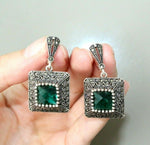 Earrings old fashioned made of precious metall and emerald stone with marcasites and shiny look. The earrings will suitto small emerald green with shoulder off sleeves and large necklline.