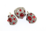 A set of sterling silver 925 jewelry with red dome-shaped earrings and a matching ring with red stones and marcasite, against a white background.