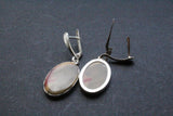 Oval flat gemstone earrings dangling made of sterling silver with leverback. The color of the stone is pale green with  red marks.