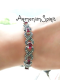 A sterling silver bracelet with red stone accents and marcasite gemstones, displayed on a wrist.